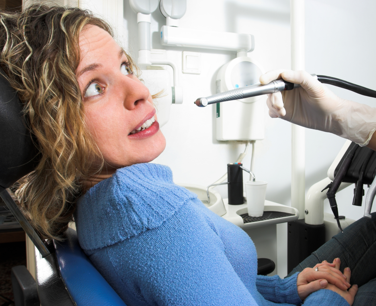 Anxious woman sitting in a dental chair looking nervous as the dentist prepares to begin treatment