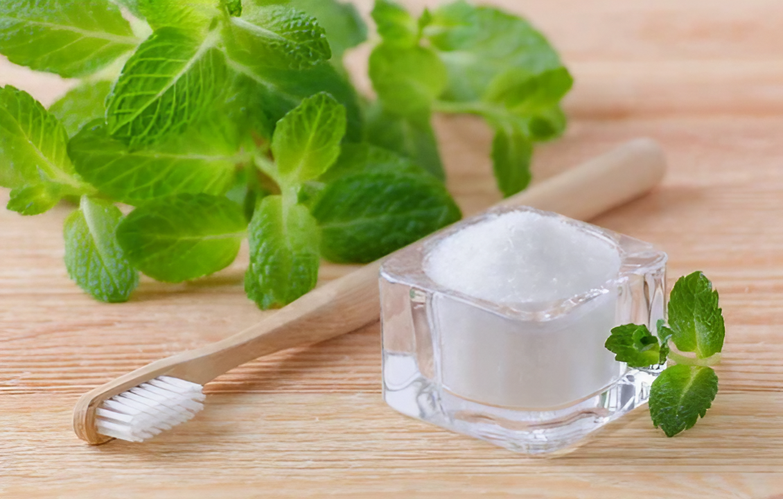 Toothbrush with mint leaves and natural mouth cleaning salt on wooden surface
